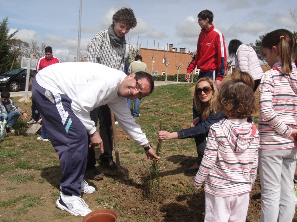 Un jóven planta un árbol bajo las indicaciones una de las técnico de Educación Ambiental.