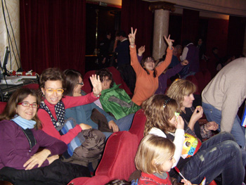 Parte del grupo saludan desde su asiento en el teatro.