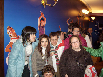 Foto de los jóvenes de AVIVA a la salida del teatro, con los carteles decorativos del teatro.