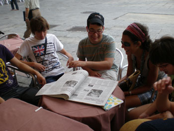Los jóvenes leen la prensa mientras esperan el desayuno en la terraza del Novelty.